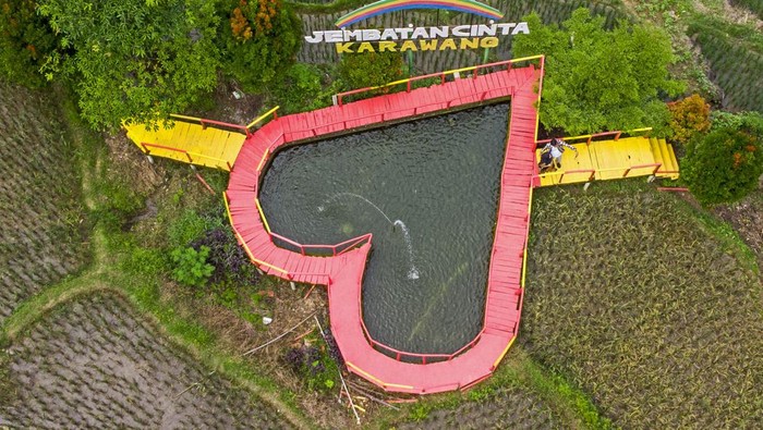 Pengunjung menikmati suasana wisata Jembatan Cinta di Desa Mekarbuana, Tegalwaru, Karawang, Jawa Barat, Minggu (9/1/2022). Menparekraf Sandiaga Uno mengatakan sektor pariwisata dan ekonomi kreatif (parekraf) dapat berkontribusi besar bagi kebangkitan ekonomi di tanah air pada tahun 2022. ANTARA FOTO/M Ibnu Chazar/foc.