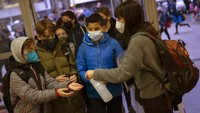 Siswa sekolah dasar mendisinfeksi tangan mereka saat mereka melanjutkan aktivitas. (AP/Emilio Morenatti)