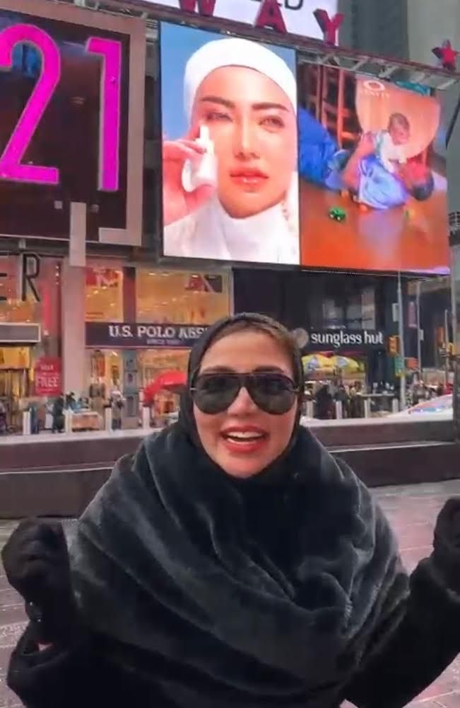 Bella Shofie saat sedang di Times Square, New York, dan mengekspresikan kebahagiaannya melihat produk kecantikan miliknya nampang di billboard iklan.