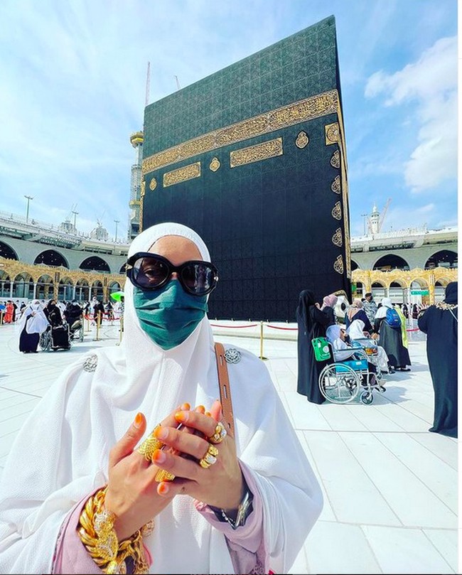 Di sebuah unggahan lain, tampak pelantun Ser Ser Ser itu difoto dengan pose berdoa sembari membelakangi Kabah. Namun, perhiasan emas yang memenuhi jemarinya bikin salfok netizen. (Foto: Instagram/@ifa_raziah)