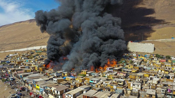 Kebakaran Hebat Landa Permukiman Migran di Chile Petugas pemadam kebakaran menunggu air selama kebakaran di lingkungan berpenghasilan rendah Laguna Verde, di Iquique, Chili, Senin, 10 Januari 2022. Menurut pihak berwenang, api menghancurkan hampir 100 rumah di lingkungan yang sebagian besar dihuni oleh migran. (Foto AP/Ignacio Munoz)