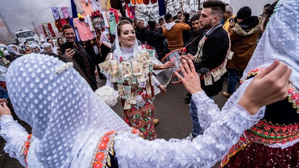Pengantin Muslim Nefie Eminkova, (kiri) dan pengantin pria Shaban Kiselov, (kanan) menari di jalan, selama hari pernikahan mereka (9/1/2022), di Ribnovo, Bulgaria. Desa Ribnovo yang terletak di pegunungan terpencil di barat daya Bulgaria ini masih tetap mempertahankan tradisi unik mereka.