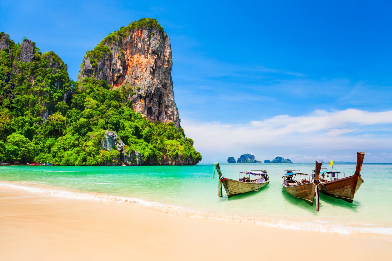 Perahu di pantai yang indah dengan tebing kapur dan air sebening kristal di Thailand