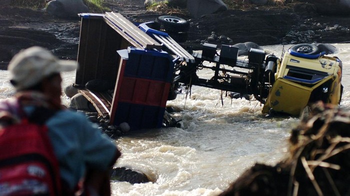 Warga memperhatikan truk yang hanyut diterjang banjir bandang Sungai Kaligung, Desa Danawarih, Kabupaten Tegal, Jawa Tengah, Selasa (11/1/2022). Truk pengangkut galian C pasir dan batu tersebut terseret banjir bandang Sungai Kaligung mencapai 150 meter dan mengakibatkan dua awak truk tewas tenggelam. ANTARA FOTO/Oky Lukmansyah/foc.