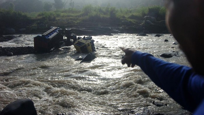 Warga memperhatikan truk yang hanyut diterjang banjir bandang Sungai Kaligung, Desa Danawarih, Kabupaten Tegal, Jawa Tengah, Selasa (11/1/2022). Truk pengangkut galian C pasir dan batu tersebut terseret banjir bandang Sungai Kaligung mencapai 150 meter dan mengakibatkan dua awak truk tewas tenggelam. ANTARA FOTO/Oky Lukmansyah/foc.