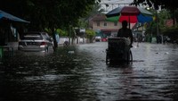 Warga berjalan menerobos banjir di Rangkasbitung, Lebak, Banten.
