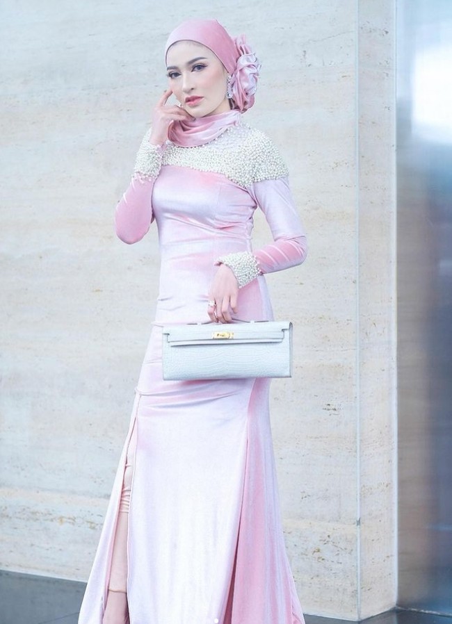 Dalam kesehariannya, Shandy Purnamasari kerap mengenakan gaun rancangan desainer lokal saat menghadiri acara formal. Seperti di foto ini, Shandy mengenakan busana karya Rio Susanto Couture. Shandy memadukannya dengan hijab pashmina satin warna pink dan membentuk sanggul berbentuk bunga di bagian samping kiri hijab. Shandy menambahkan aksesori anting yang menjuntai. Foto: Dok. Instagram @shandypurnamasari.