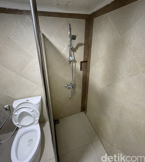 Toilet di kamar hotel Grand Inna Samudra Beach. Ada air panas dan kesan bersih terlihat di foto ini. Di samping foto ada wastafel dengan kaca yang besar.