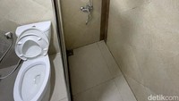 Toilet di kamar hotel Grand Inna Samudra Beach. Ada air panas dan kesan bersih terlihat di foto ini. Di samping foto ada wastafel dengan kaca yang besar.