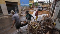 Warga memindahkan barang-barang yang rusak dan makanan busuk di luar rumah mereka setelah banjir di Raposos.