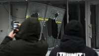 Orang-orang mengambil foto jendela yang rusak di gedung media center di Almaty, Kazakhstan. Kehidupan di Almaty paling terkena dampak kekerasan selama protes. (AP/Vladimir Tretyakov)