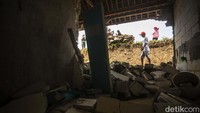 Warga melintas di depan rumah yang jebol akibat longsornya tanggul Sungai Citarum di Desa Lenggah Jaya, Cabangbungin, Kabupaten Bekasi, Rabu (12/1/2021).