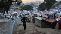 Pengungsi melintas di depan deretan tenda darurat hampir satu bulan usai gempa besar melanda Haiti, (6/2/2010). John Moore/Getty Images.