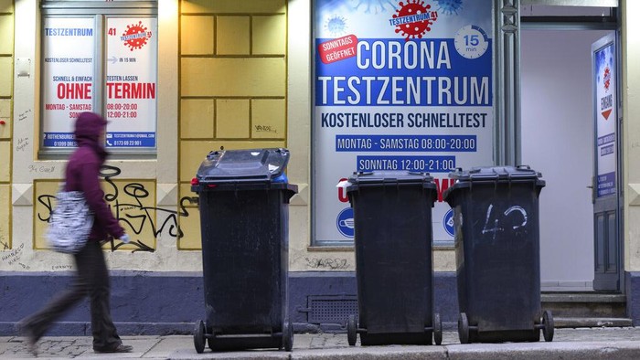 A woman walks past a coronavirus test center in Neustadt district in Dresden, Germany, Tuesday, Jan. 11, 2022. (Robert Michael/dpa via AP)