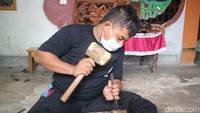 Ulik sapaannya tengah sibuk membuat patung dan ukiran wajah dari kayu di rumahnya, Kamis (13/1). Terlihat Ulik tengah duduk di lantai. Dia terlihat membuat sebuah asbak. Tangannya terlihat luwes memahat asbak dari kayu.