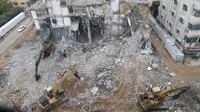 Pekerja Palestina menggunakan backhoe untuk menghancurkan dan memindahkan bagian dari sebuah bangunan, yang rusak akibat serangan udara Israel selama perang Israel dengan penguasa Hamas di Gaza Mei lalu, di lingkungan al-Rimal tengah Kota Gaza, (23/12/2022).