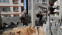 Warga Palestina membangun tembok gedung apartemen baru di pusat lingkungan al-Rimal Kota Gaza, Senin, (10/1/2022). 