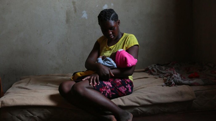 Nestapa Remaja Zimbabwe Terjerat Kemiskinan dan Pernikahan Dini Tanaka Rwizi, right, a pregnant 16 year old teenager mother, stands with her family in their residence in the poverty stricken Mbare township in Harare, Zimbabwe, Saturday, Nov. 13, 2021. Tanaka, who dropped out of school after falling pregnant in February 2021, stays with her unemployed uncle in a single room divided by a curtain. (AP Photo/Tsvangirayi Mukwazhi)