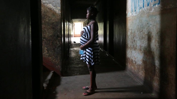 Tanaka Rwizi, right, a pregnant 16 year old teenager mother, stands with her family in their residence in the poverty stricken Mbare township in Harare, Zimbabwe, Saturday, Nov. 13, 2021. Tanaka, who dropped out of school after falling pregnant in February 2021, stays with her unemployed uncle in a single room divided by a curtain. (AP Photo/Tsvangirayi Mukwazhi)