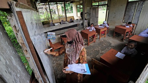 Pelajar kelas III (kiri) dan II (kanan) SDN 217 Pamenang mengikuti kegiatan belajar mengajar di ruang kelas bekas bangunan perumahan guru di Dusun Tuo, Pamenang, Merangin, Jambi, Kamis (13/1/2022). Sejak lima tahun terakhir, belasan siswa dari tiga tingkatan kelas di sekolah tersebut terpaksa melakukan kegiatan belajar mengajar di bangunan bekas perumahan guru yang sudah tidak layak huni karena terbatasnya jumlah ruangan. ANTARA FOTO/Wahdi Septiawan/rwa.
