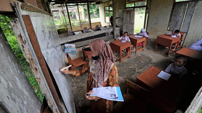 Nestapa Siswa di Jambi Belajar di Bangunan Tak Layak Pelajar kelas III (kiri) dan II (kanan) SDN 217 Pamenang mengikuti kegiatan belajar mengajar di ruang kelas bekas bangunan perumahan guru di Dusun Tuo, Pamenang, Merangin, Jambi, Kamis (13/1/2022). Sejak lima tahun terakhir, belasan siswa dari tiga tingkatan kelas di sekolah tersebut terpaksa melakukan kegiatan belajar mengajar di bangunan bekas perumahan guru yang sudah tidak layak huni karena terbatasnya jumlah ruangan. ANTARA FOTO/Wahdi Septiawan/rwa.