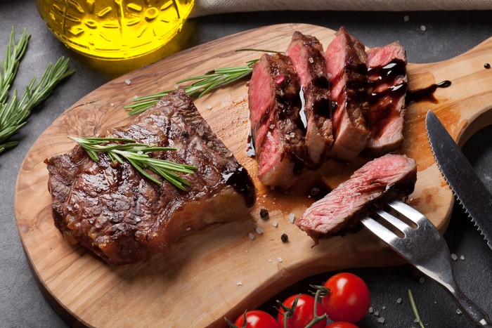 Grilled sliced beef steak on cutting board over stone table