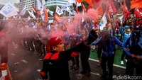 Seorang buruh tampak membawa flare saat ikut serta dalam aksi unjuk rasa di depan Gedung DPR RI.