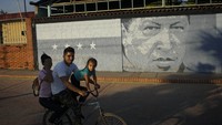 Mural bergambar Chavez muda di tembok kota. Chavez lahir pada 23 Juli 1954 dan besar di dunia militer. Kemudian dia melakukan serangkaian kudeta. Saat menjabat presiden, ia menasionalisasi perusahaan migas untuk mensubsidi kebutuhan rakyat miskin.