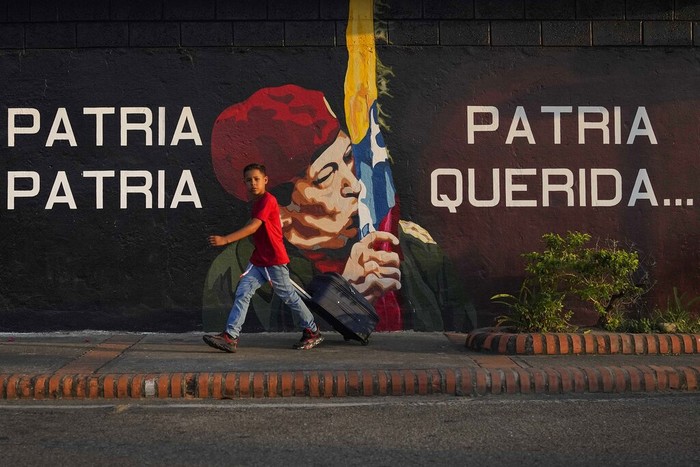 Hugo Chavez A boy pulls a suitcase on wheels as he walks past a mural of the late Venezuelan President Hugo Chavez in Chavez's hometown of Sabaneta, in Barinas state in Venezuela, Friday, Jan. 7, 2022. The country's highest court disqualified opposition candidate Freddy Superlano as he was leading the count in November's gubernatorial election in Barinas, apparently defeating Argenis Chavez, the brother of late President Hugo Chavez's, and ordered a re-run on Jan. 9. (AP Photo/Matias Delacroix)