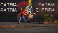 Anak kecil melintasi di depan mural Hugo Chavez di kampung halaman Chavez di Sabaneta, Barinas (7/1/2022). Saudara Chavez, Argenis Chavez menjadi salah satu kandidat gubernur pada pemilihan ulang, Sabtu (9/1/2022).