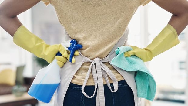 Shot of an unrecognisable woman using rubber gloves and disinfectant to clean her home