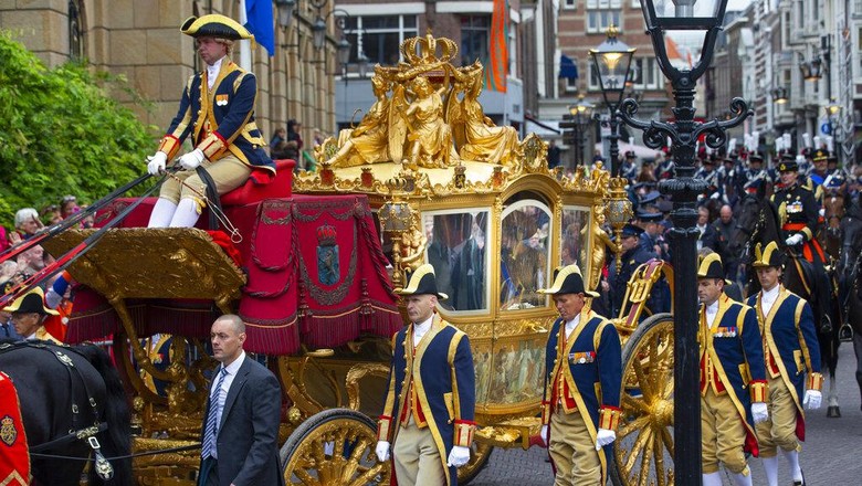 Kereta kuda emas Belanda In this Tuesday, Sept. 17, 2013, file image, Netherlands King Willem-Alexander and his wife Queen Maxima arrive in the Golden Carriage at Noordeinde Palace, after the King officially opened the new parliamentary year in The Hague, Netherlands. Even the horse-drawn Golden Carriage, currently undergoing a lengthy restoration but traditionally used to carry the Dutch monarch to the state opening of Parliament each year, has drawn criticism because one of its panels, center, is decorated with a painting depicting Africans and Asians carrying goods to present to their colonial masters. (AP Photo/Peter Dejong, file)