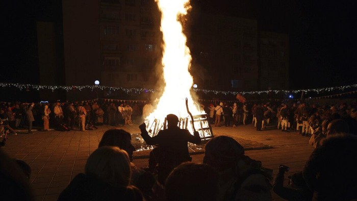 Potret Festival Topeng di Bulgaria, Ritual Kuno Usir Roh Jahat Mask dancers perform an age-old ritual chasing the evil spirits away on the streets of Batanovci, Bulgaria, late Thursday, Jan. 13, 2022. Every winter in villages across the Balkan country, men, women, and children dressed up in ritual masks and costumes perform their vibrant dances around bonfires. For a second year now, the festival has extra significance: people hope it will bring relief from the coronavirus pandemic woes. (AP Photo/Valentina Petrova)