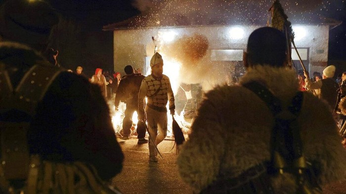 Mask dancers perform an age-old ritual chasing the evil spirits away on the streets of Batanovci, Bulgaria, late Thursday, Jan. 13, 2022. Every winter in villages across the Balkan country, men, women, and children dressed up in ritual masks and costumes perform their vibrant dances around bonfires. For a second year now, the festival has extra significance: people hope it will bring relief from the coronavirus pandemic woes. (AP Photo/Valentina Petrova)