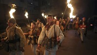 Penari membawa obor saat mereka melakukan ritual kuno mengusir roh jahat di jalan-jalan Batanovci, Bulgaria.