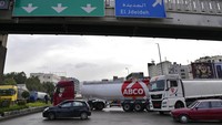 Mobil berbelok di jalan raya utama yang diblokir oleh truk tangki dan bus selama pemogokan umum. (AP/Hussein Malla)