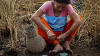 Seorang warga mengikat pakaiannya untuk melindungi kakinya dari serangga sebelum masuk ke danau untuk berburu ikan dalam gelaran festival Bhogali Bihu.