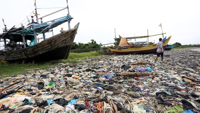 Nelayan beraktivitas di dekat tumpukan sampah yang berserakan di Pantai Dadap, Indramayu, Jawa Barat, Sabtu (15/1/2022). Sampah yang sebagian besar dari limbah rumah tangga dan plastik tersebut terseret arus dan menumpuk di pantai sehingga mengganggu aktivitas nelayan. ANTARA FOTO/Dedhez Anggara/hp.