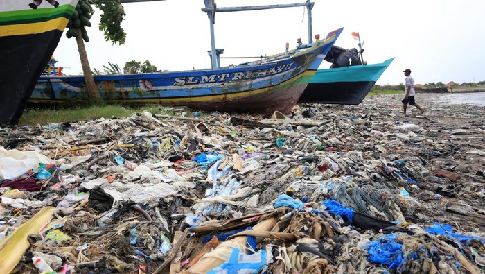 Nelayan beraktivitas di dekat tumpukan sampah yang berserakan di Pantai Dadap, Indramayu, Jawa Barat, Sabtu (15/1/2022). Sampah yang sebagian besar dari limbah rumah tangga dan plastik tersebut terseret arus dan menumpuk di pantai sehingga mengganggu aktivitas nelayan. ANTARA FOTO/Dedhez Anggara/hp.