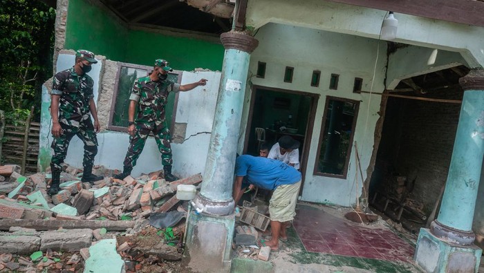 Warga dibantu personel TNI membersihkan bangunan rumahnya yang rusak di Sumur, Pandeglang, Banten, Sabtu (15/1/2022). Sebanyak 1.231 rumah dengan rincian 226 rusak berat, 290 rusak sedang, 715 rusak ringan, dan 14 puskesmas di tiga daerah di Banten rusak akibat gempa bumi magnitudo 6,6 SR yang terjadi pada Jumat (14/1) kemarin. ANTARA FOTO/Muhammad Bagus Khoirunas/HP.