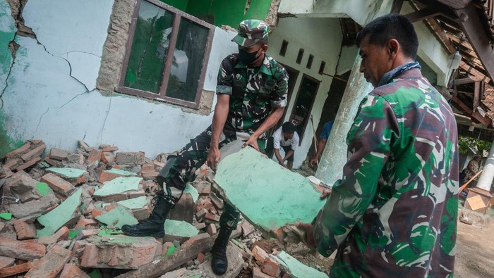 SEBANYAK 1.231 RUMAH RUSAK AKIBAT GEMPA BANTEN Warga dibantu personel TNI membersihkan bangunan rumahnya yang rusak di Sumur, Pandeglang, Banten, Sabtu (15/1/2022). Sebanyak 1.231 rumah dengan rincian 226 rusak berat, 290 rusak sedang, 715 rusak ringan, dan 14 puskesmas di tiga daerah di Banten rusak akibat gempa bumi magnitudo 6,6 SR yang terjadi pada Jumat (14/1) kemarin. ANTARA FOTO/Muhammad Bagus Khoirunas/HP.
