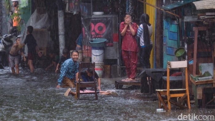 Hujan deras membuat jalanan di Pademangan Timur, Jakarta Utara, tergenang. Anak-anak sekitar memanfaatkan momen tersebut dengan bermain di genangan.