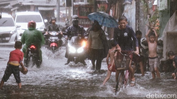 Hujan deras membuat jalanan di Pademangan Timur, Jakarta Utara, tergenang. Anak-anak sekitar memanfaatkan momen tersebut dengan bermain di genangan.