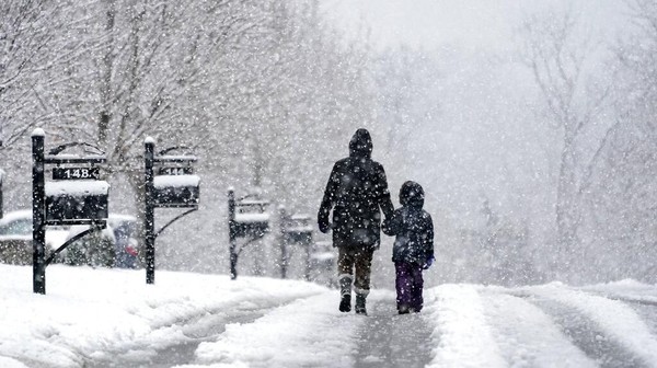 Orang-orang berjalan-jalan saat salju turun Minggu, (16/1/2022), di Nolensville, Tennessee. AP/Mark Humphrey