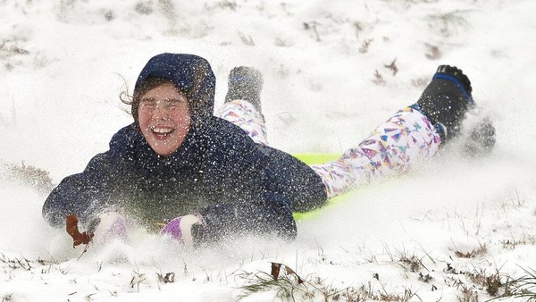 Clara Kozakiewicz (9), berwajah penuh salju saat dia naik kereta luncur di Sekolah Dasar Moore Magnet di Winston-Salem, N.C., Minggu, (16/1/2022). Wilayah Triad menerima 2-3 inci salju dan hujan es. AP/Walt Unks