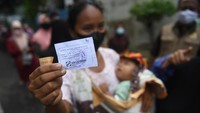 Warga menunjukkan kupon saat mengantre untuk membeli minyak goreng dengan harga murah saat operasi pasar di Johar Baru, Jakarta.