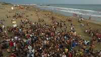 Remaja berkumpul sore hari di pantai di Pinamar, provinsi Buenos Aires, Argentina, Sabtu, (15/1/2022). Di tengah meningkatnya infeksi oleh varian baru Omicron dari COVID 19, ribuan wisatawan di Argentina memenuhi pantai saat musim panas terpanas dalam beberapa tahun terakhir. (AP/Rodrigo Abd)