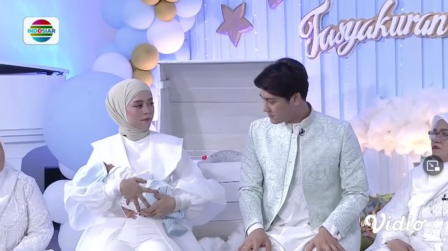 Sementara sang suami, Rizky Billar, tampak memakai kemeja kerah tinggi dan celana putih yang dipadu outer berpotongan tailoring aksen emboss. Foto: Instagram/@askar_photography, YouTube Indosiar