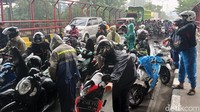 Mereka berteduh agar terhindar dari guyuran hujan.