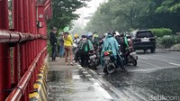 Sebagian pengendara melanjutkan perjalanan usai memakai jas hujan.